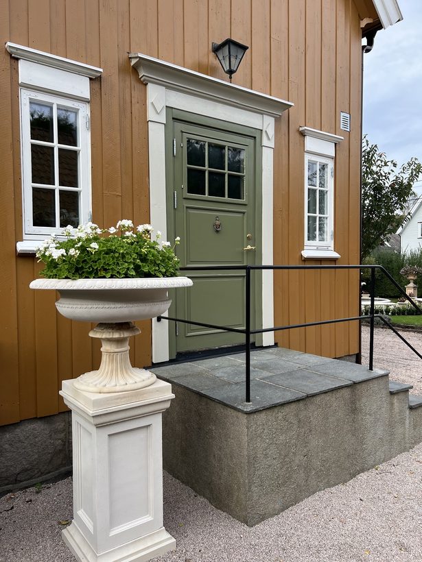 Hvit urne på pidestall ved inngangsdøren til villaen i Greåkerveien 149